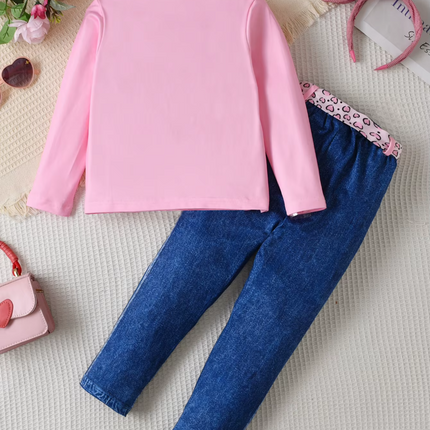 Pink long-sleeve top and blue jeans on a textured surface with decorative elements.

