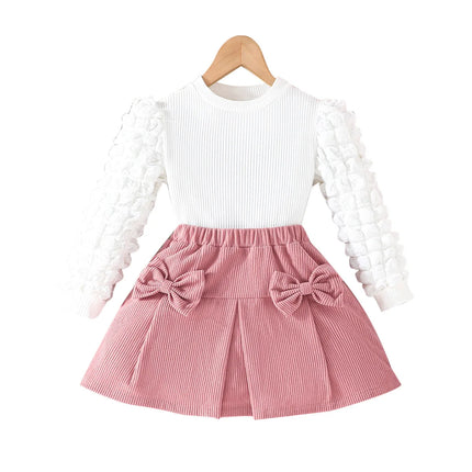 White long-sleeve top and pink skirt with bow details on a white background

