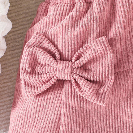 Close-up of a pink ribbed sweater with a large bow detail.

