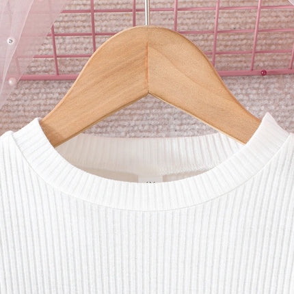 White sweater on a wooden hanger with a pink grid background

